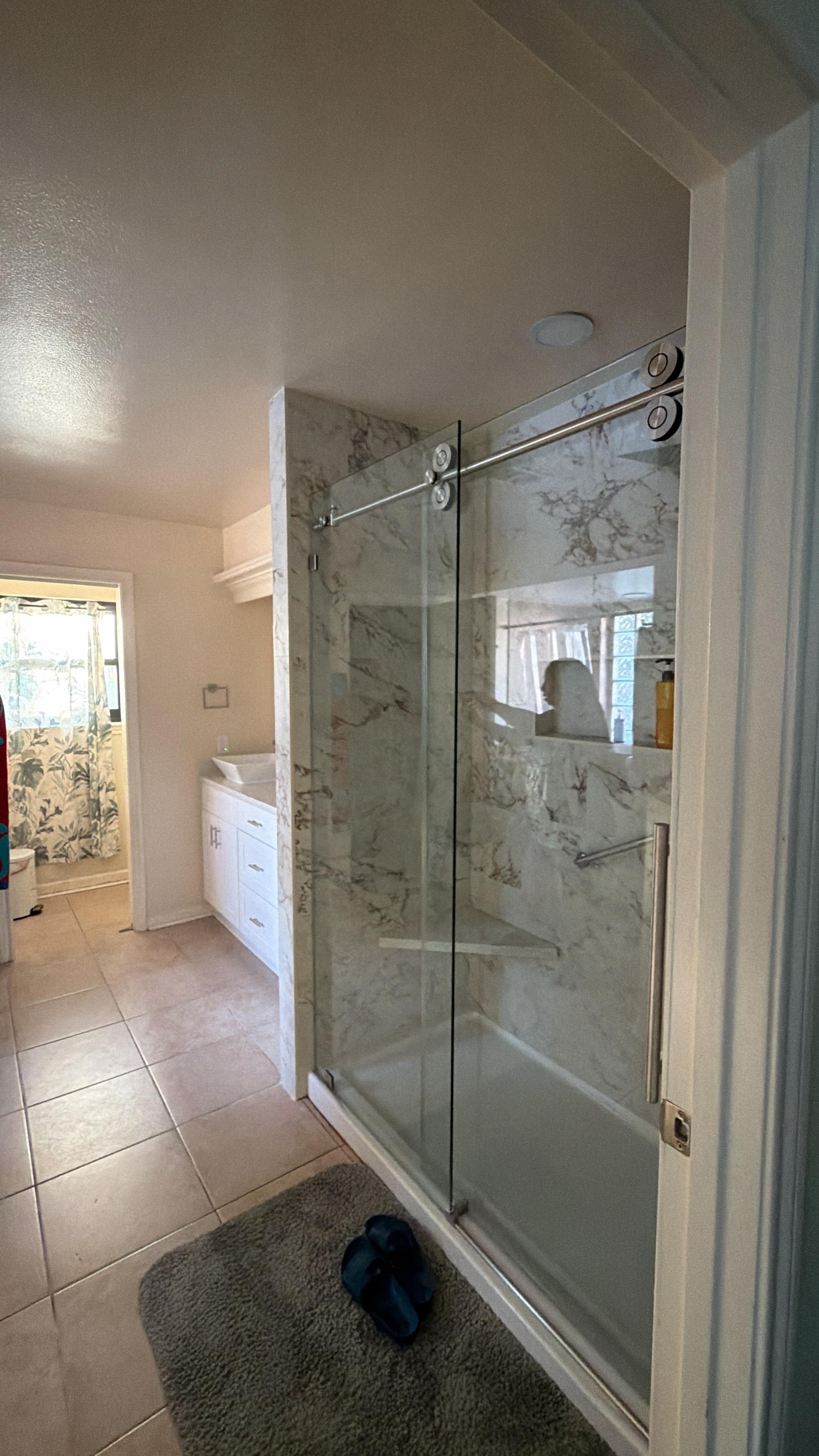 Frameless glass shower with marble tile and vanity